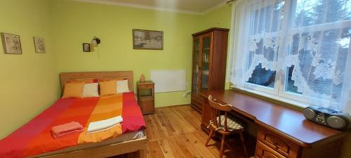 1 dormitorio con cama, escritorio y ventana en Domek Drewniany, en Nowa Wola