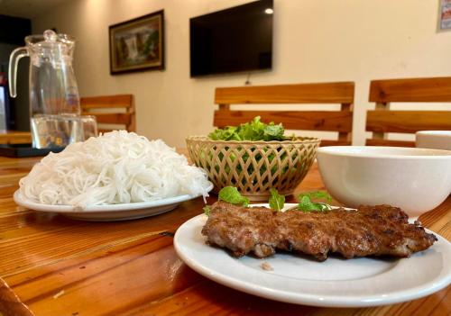a wooden table with plates of food and noodles at Tam Coc Phuong Nhi Homestay in Ninh Binh