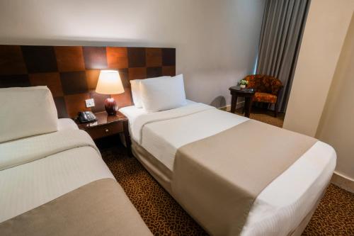 a hotel room with two beds and a table with a lamp at Ayass Hotel in Amman