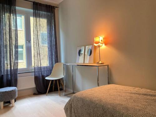 - une chambre avec un lit, une lampe et une chaise dans l'établissement PinkRose CityStay Järnvågen, à Göteborg