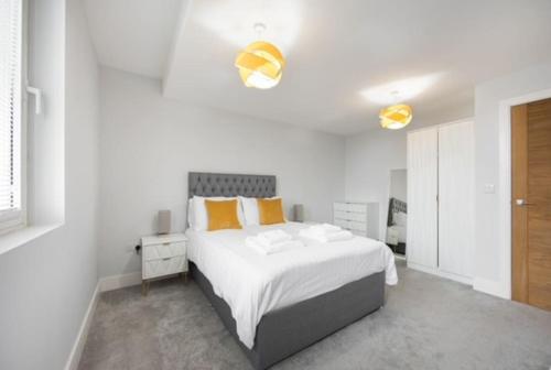 a white bedroom with a large bed with yellow pillows at Cosy, Bright and Spacious Flat in Brentwood