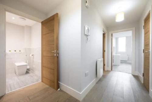 a white bathroom with a toilet and a door at Cosy, Bright and Spacious Flat in Brentwood