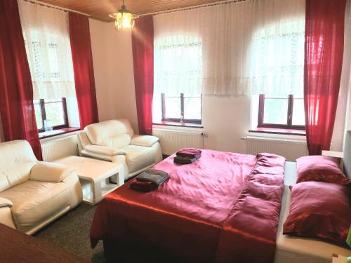 a bedroom with a bed and two chairs and windows at Gasthof Oberschmiede in Auf der Wiese
