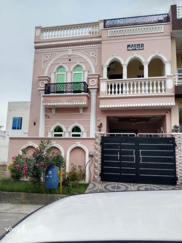 een roze gebouw met een hek ervoor bij Shah Guest House in Jhelum