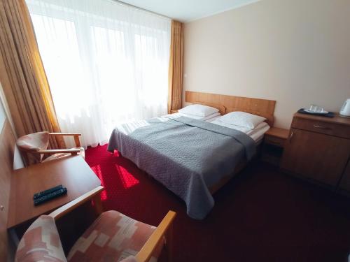 niewielka sypialnia z łóżkiem i oknem w obiekcie Libra Mrzeżyno w mieście Mrzeżyno