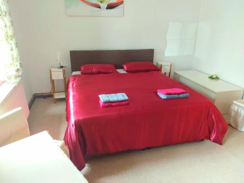 a bedroom with a red bed with two pillows on it at Gasthof Oberschmiede in Auf der Wiese