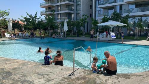 a group of people sitting in a swimming pool at דירת פאר על הים VIP apartment near the beach in H̱adera