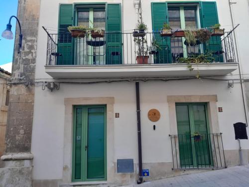 een gebouw met groene deuren en een balkon bij A Calata in Noto