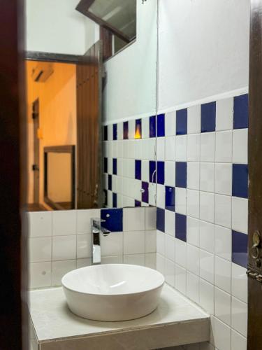 uma casa de banho com um lavatório branco e azulejos azuis e brancos. em Moonbeam Kandy em Kandy