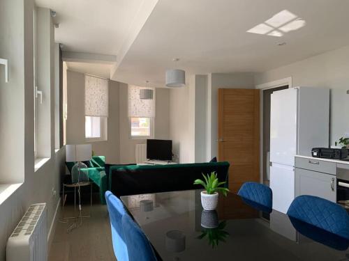 sala de estar con mesa de cristal y sillas azules en Two bedroom, modern spacious apartment., en Brentwood