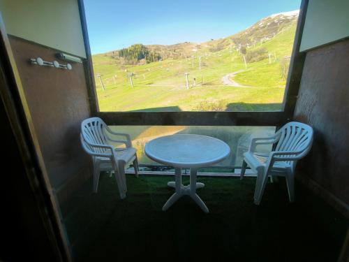 une table et deux chaises dans une pièce avec une fenêtre dans l'établissement studio le corbier, au Corbier