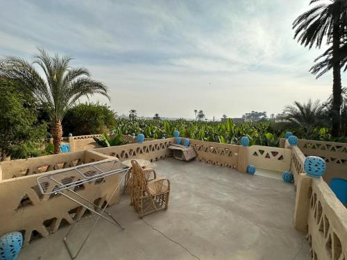 a patio with tables and chairs and palm trees at Villa Rebecca Professor's paradise in Luxor