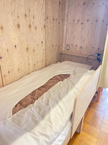 a large bed in a room with wooden walls at ゲストハウスあさひのお宿 in Kurodahara