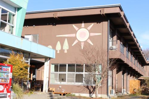 a building with a sun painted on the side of it at ゲストハウスあさひのお宿 in Kurodahara