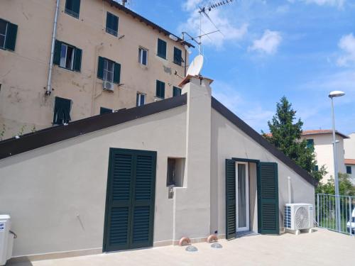 a building with green shutters and two children in front at Casa n 1 con parcheggio privato e colonnina ricarica in Livorno