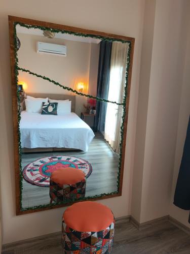 a mirror in a bedroom with a bed and two stools at Deniz Manzaralı Müstakil ev Aybalik in Ayvalık