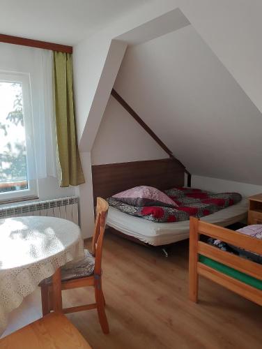 a room with two beds and a table and a window at LEŚNA OSADA in Tuchlin