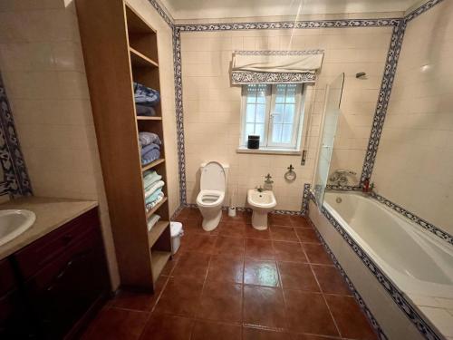La salle de bains est pourvue de toilettes, d'une baignoire et d'un lavabo. dans l'établissement Fantastic house swimmingpool jacuzzi horses, à Alcobaça