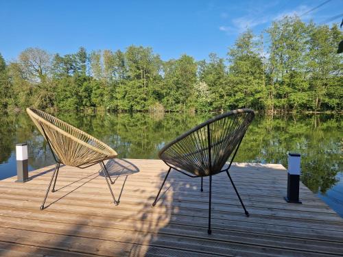 zwei Stühle auf einem Steg neben einem See in der Unterkunft Chalet bord de l'eau avec spa privatif in Longpré-les-Corps-Saints