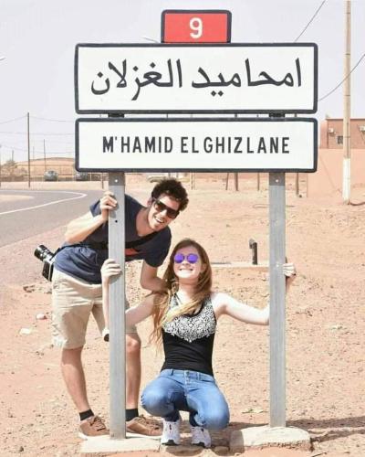 a man and a woman posing under a street sign at Mhamid Tours berbère in Mhamid