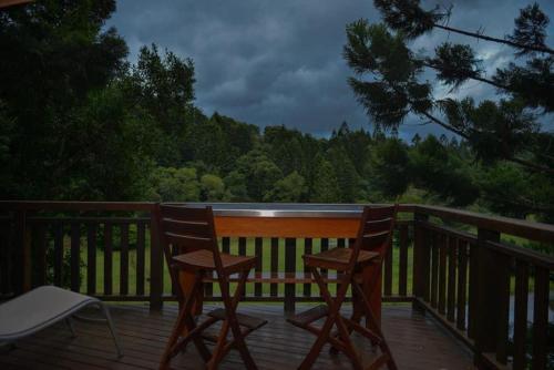 two chairs and a table on a wooden deck at Cottage in The Woods, Maleny in Maleny