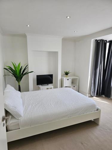 ein weißes Schlafzimmer mit einem Bett und einem TV in der Unterkunft Mirandas Place in Gillingham