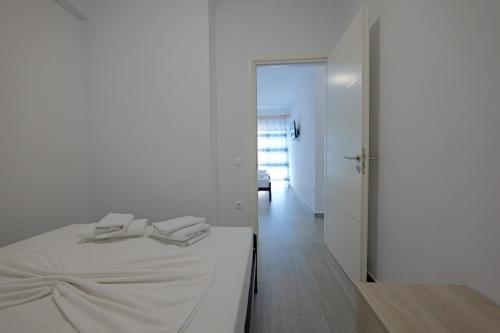 a white bedroom with a bed and a hallway at Eduard Lagji Apartament in Lukovë