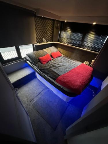 a bed with two red pillows in a room at YACHT "X" - 44 FOOT MODERN YACHT ON 5 STAR OCEAN VILLAGE MARINA - minutes away from city centre and cruise terminals, Free parking ,SPA package available! in Southampton