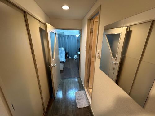 einen Flur, der zu einem Zimmer mit Bad führt in der Unterkunft Guest House Raffine HAKATA in Fukuoka