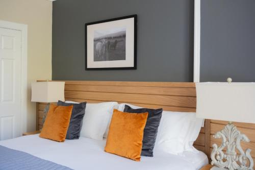 a bedroom with a bed with orange and grey pillows at Glen Mhor Hotel at Uile-bheist 'Brewstillery' in Inverness
