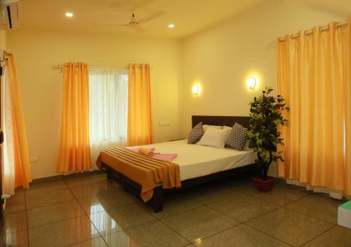 a bedroom with a large bed with orange curtains at Marari Blue Waves in Mararikulam