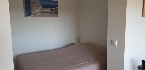 - un lit dans une chambre avec une photo sur le mur dans l'établissement Studio meublé 3 étoiles, au Lavandou