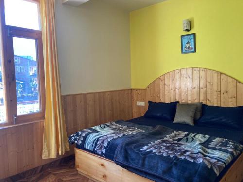 a bedroom with a bed with a wooden headboard and a window at Namha Stay by Negi Wooden House in Manāli