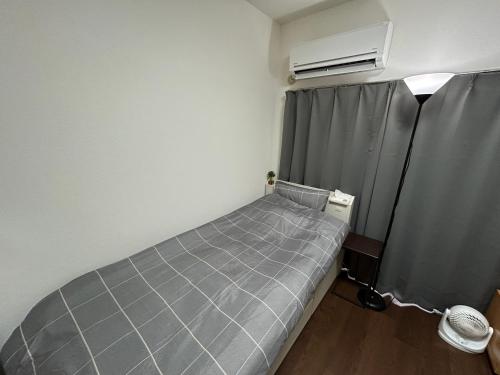 ein kleines Schlafzimmer mit einem Bett und einem Fenster in der Unterkunft Guest House Raffine HAKATA in Fukuoka