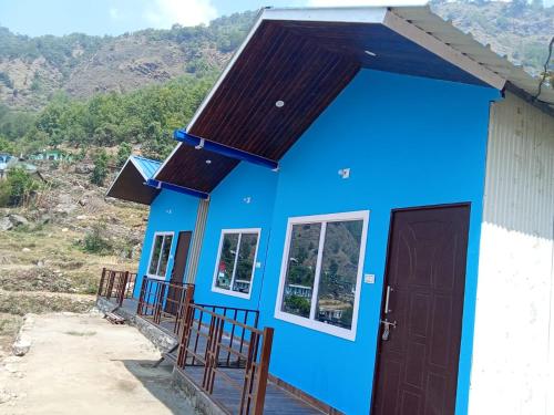 une maison bleue avec une montagne en arrière-plan dans l'établissement Lake Haven Resort, Sari, Chopta, à Sari