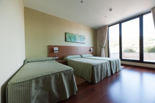 Habitación de hotel con 2 camas y ventana grande. en Hotel Restaurante Canzana en Pola de Laviana