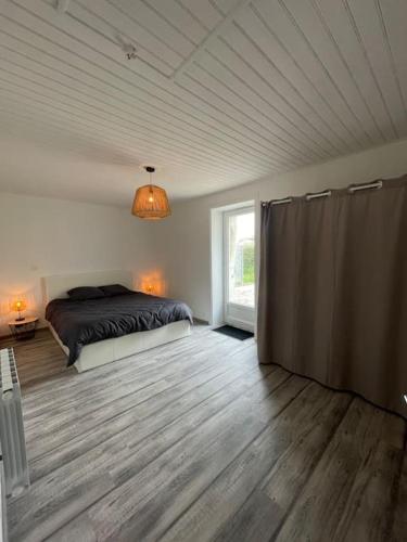 une chambre avec un lit et une grande fenêtre dans l'établissement Maison proche de la Mer !, à Grues