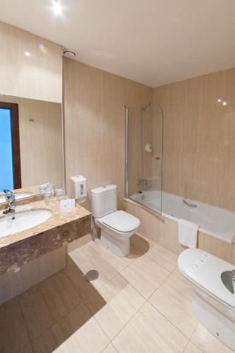 a bathroom with a toilet and a tub and a sink at Hotel Restaurante Canzana in Pola de Laviana