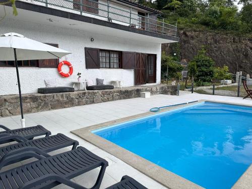 uma piscina com duas cadeiras e um guarda-sol em Casa dos Avós em Gerês