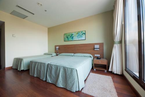 a bedroom with two beds and a window at Hotel Restaurante Canzana in Pola de Laviana