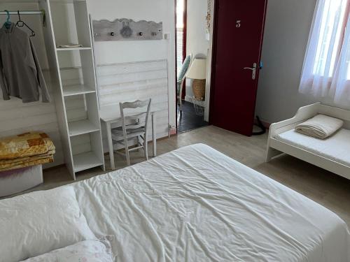 une chambre avec un lit blanc et une chaise dans l'établissement Charmante maison landaise, à Soustons