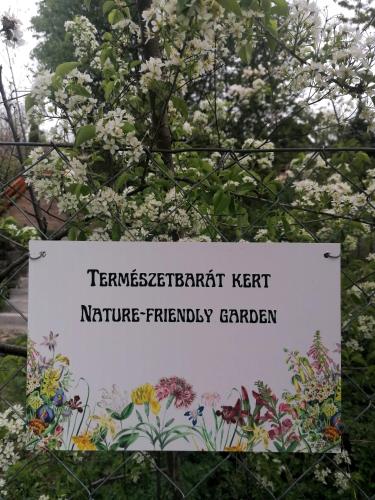 a sign in front of a tree with flowers at Barkóca és Szépkilátás Vendégház / Cabin in Kismaros