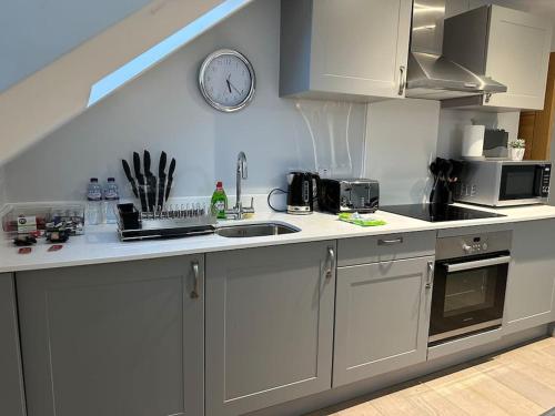 a kitchen with a sink and a clock on the wall at Modern, spacious with s/king bed Apartment in Brentwood