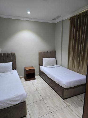 a room with two beds and a side table at ماجيك سويت الرقعى Magic Suite AlRaggi in Kuwait