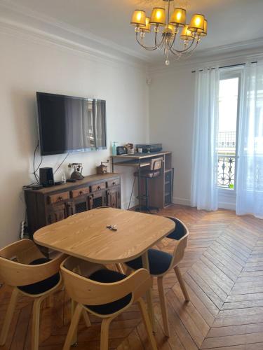 une salle à manger avec une table en bois et une télévision dans l'établissement Appartement ARC DE TRIOMPHE, à Paris