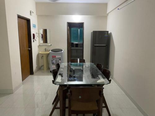 een tafel en stoelen in een kamer met een koelkast bij Service Apartment in Dhaka