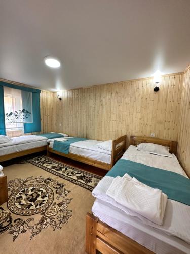a room with three beds and a rug at AKJOL guest house in Teploklyuchinskoye