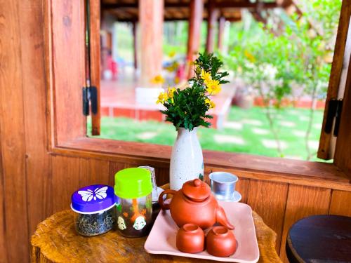 einen Tisch mit einer Teekanne und eine Vase mit Blumen in der Unterkunft Vườn Hoa Măng Đen Village in Kon Plong