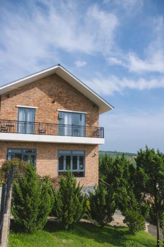a brick house with a balcony and trees at SEN VILLA Boutique in Bao Loc