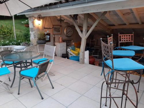 een patio met een tafel en stoelen en een parasol bij Maison La Thébaïde in Castéra-Lectourois